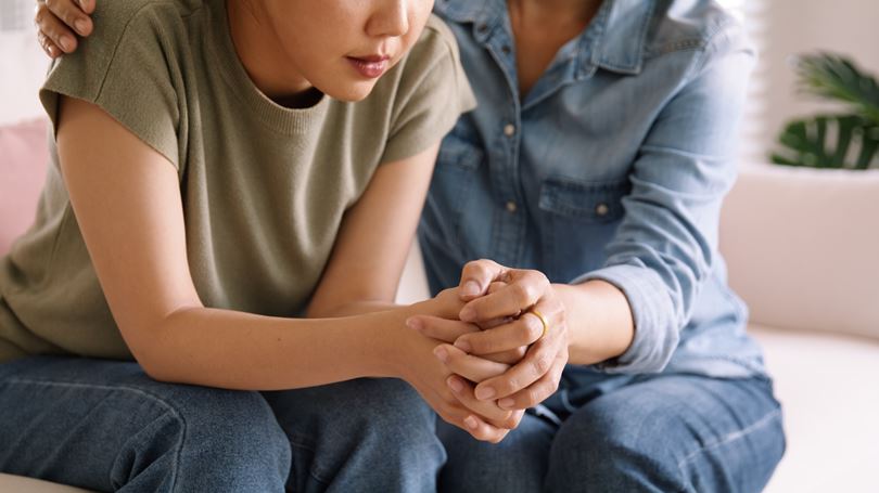 A woman being comforted by a colleague after experiencing workplace harassment